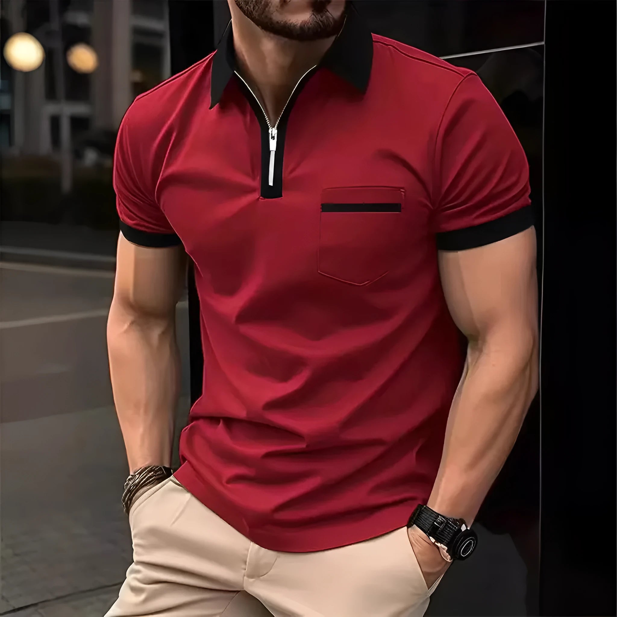 Man wearing a grey and navy blue casual t-shirt with a chest pocket and silver zip decoration detail.
