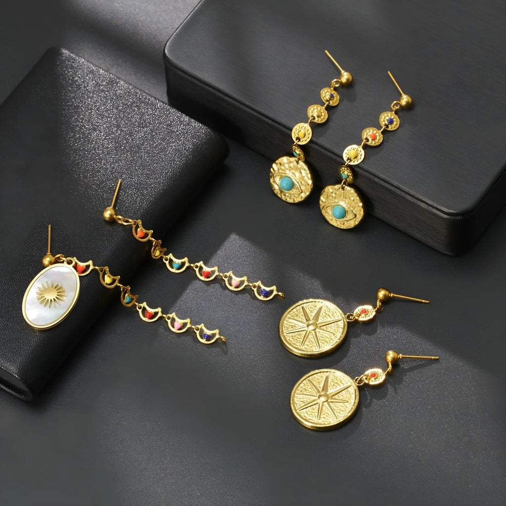 Three pairs of geometric stainless steel earrings: star, eye, and shell sun designs.