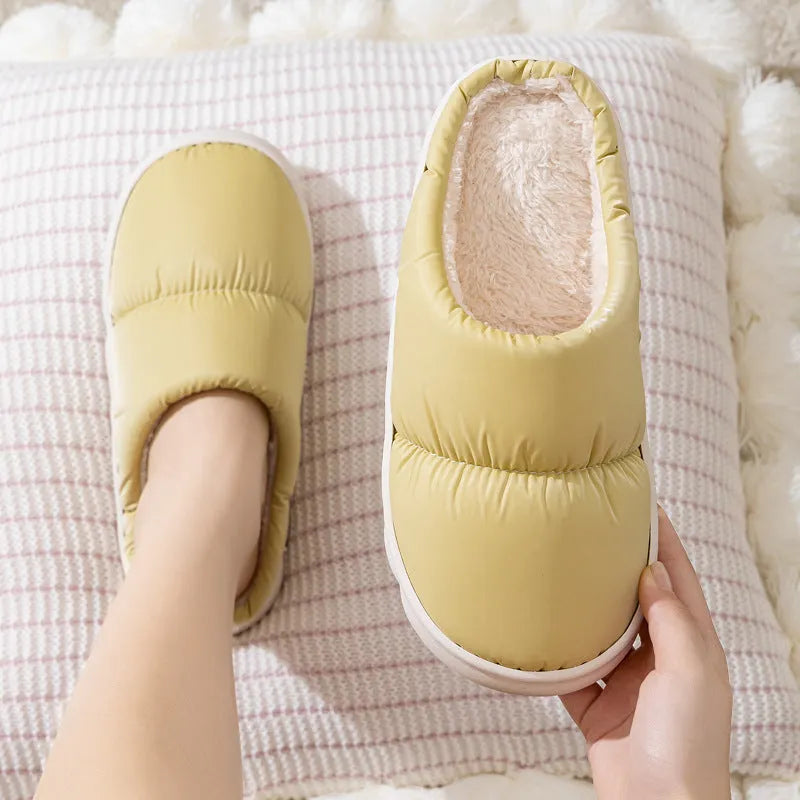 Blue down cotton indoor slippers with thick rubber sole and plush lining on a wooden floor.