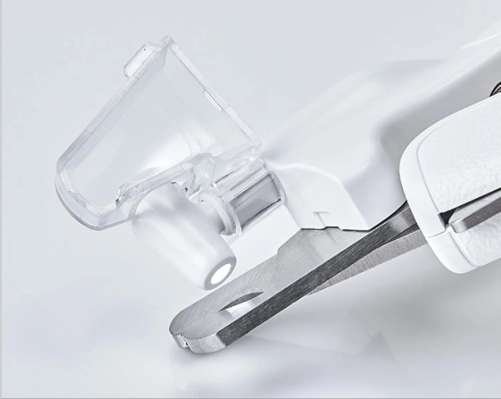 White pet nail clippers with LED light, anti-splash guard, and a nail file on a table.