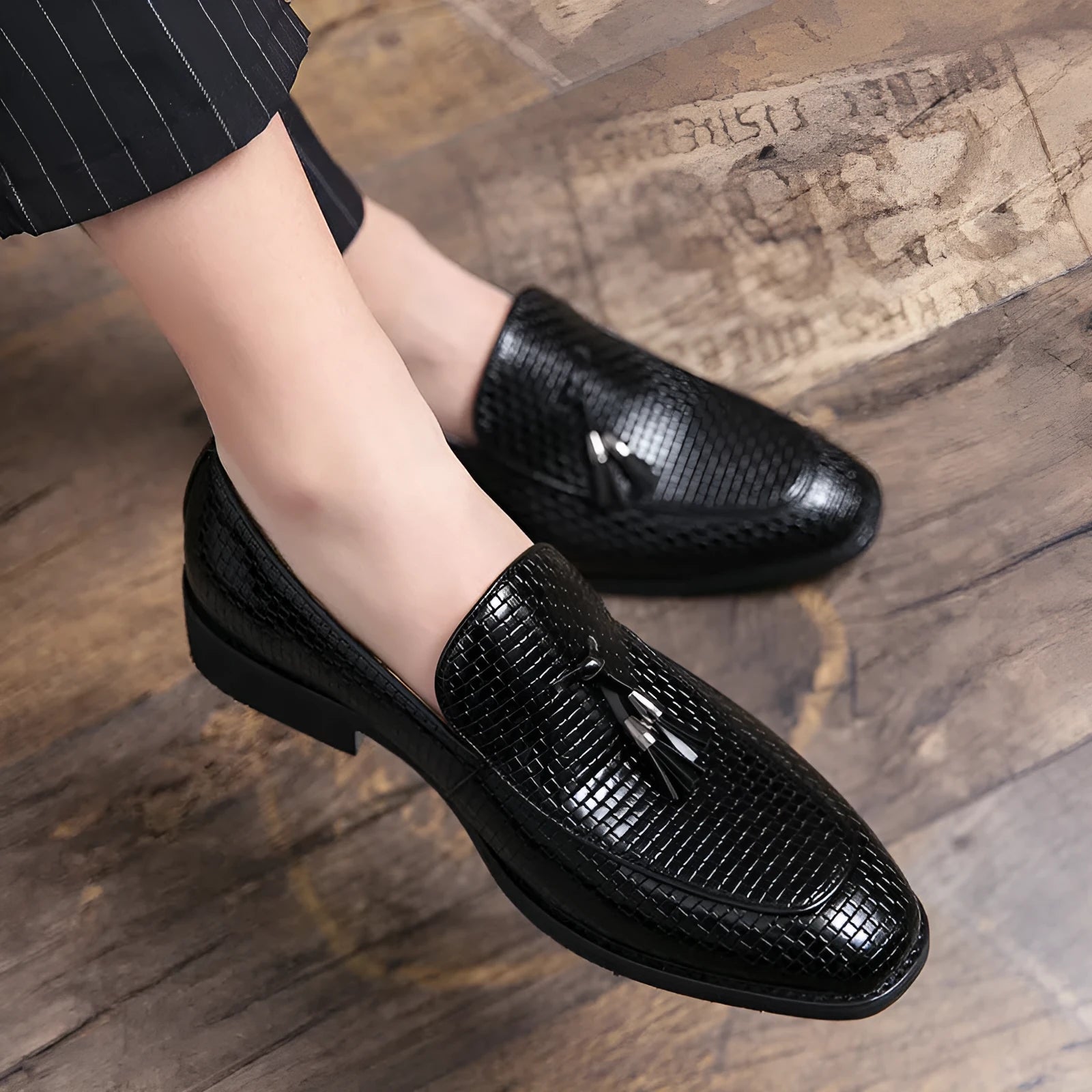 Men's black pointed slip-on business shoes with tassel detail on artificial PU upper.