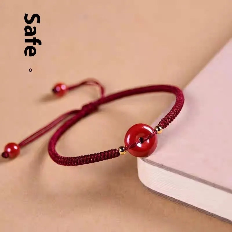 Heart-shaped cinnabar bead on an adjustable knot rope bracelet with a decorative peace buckle closure.