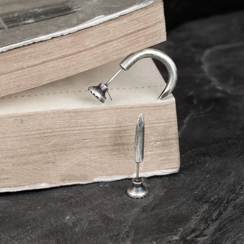 Close-up of a sterling silver S925 punk-style earring shaped like a retro nail, shown on a hook back.