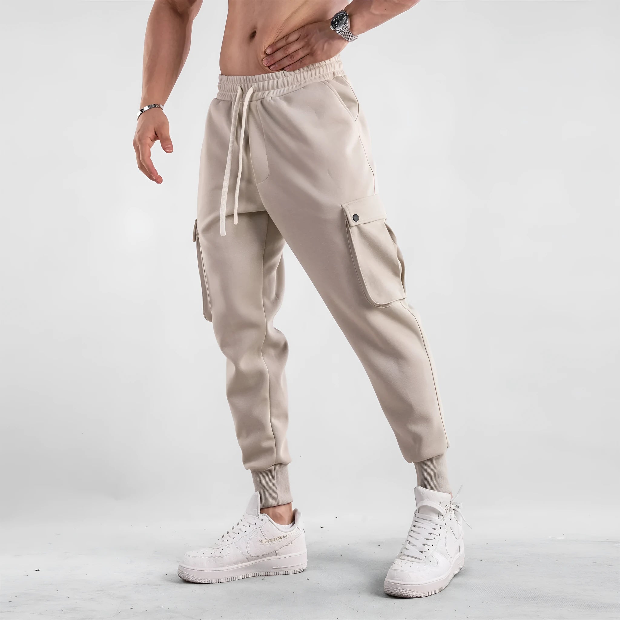 Men's loose fit cotton trousers with ankle-tied cuffs and multiple pockets in a light grey colour.