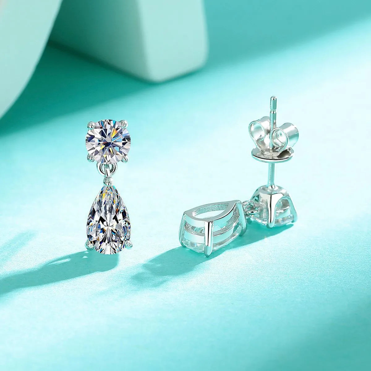 Women's sterling silver geometric stud earrings with round and water drop moissanite stones.