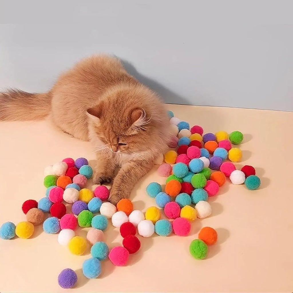 Cat toy ball launcher gun in hand with 20 soft plush pom pom balls for interactive fetch play