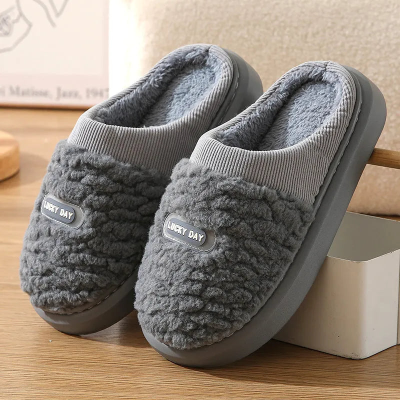 Men's grey plaid rabbit hair slippers with a thick sole, shown on a wooden floor.