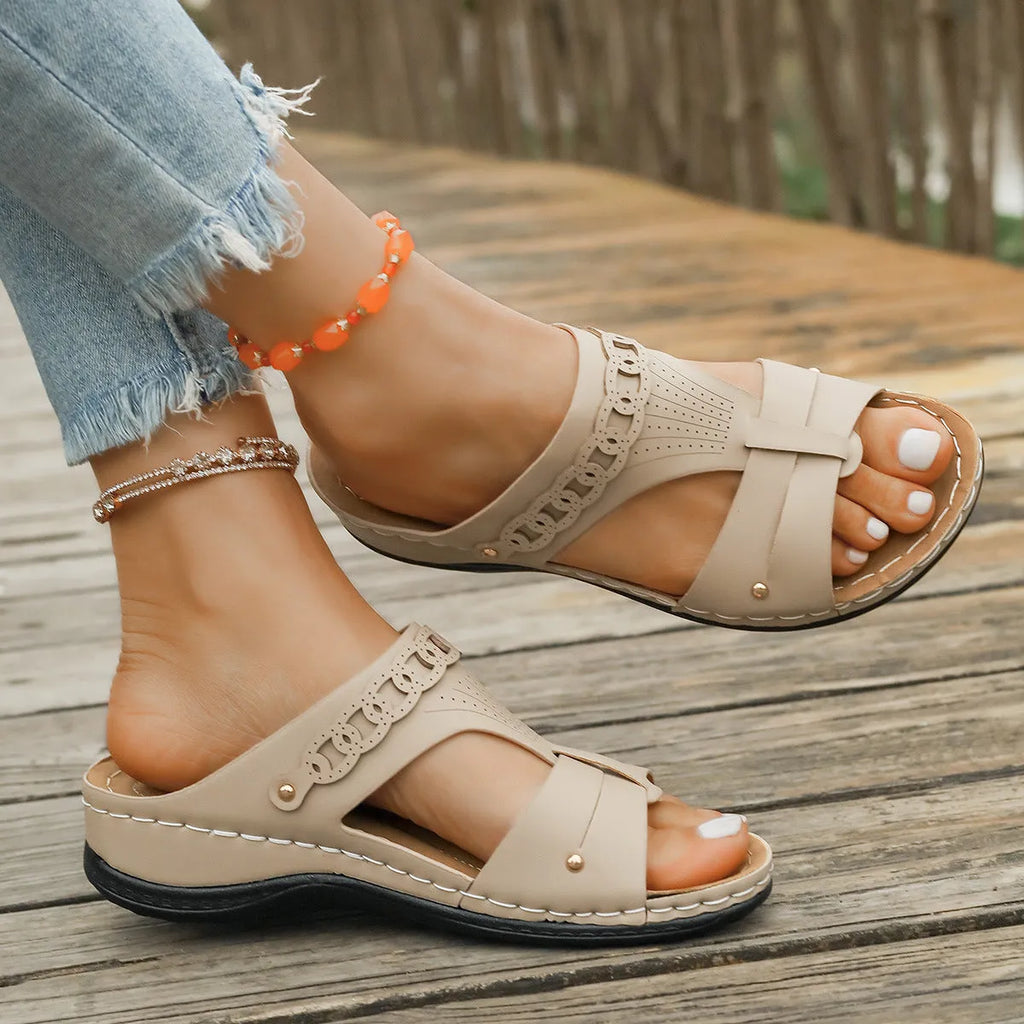 A pair of beige Roman-style slope heel slippers with a fish mouth toe holder on a plain background.
