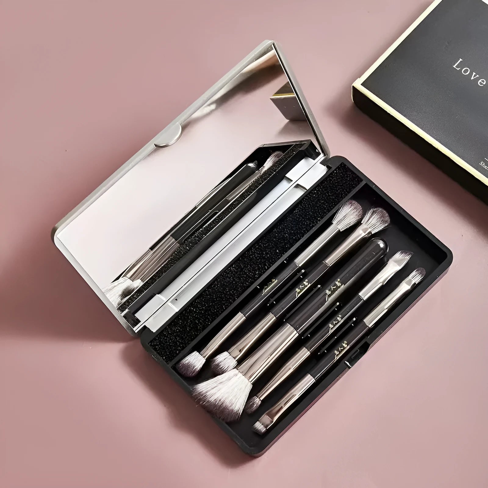 Compact makeup brush set with mirror showing silver or gold finish brushes with artificial fibre heads