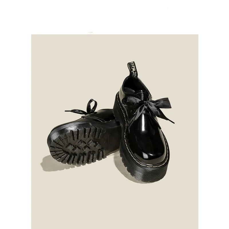 Women's black leather shoes with thick soles, cross straps, and ribbon lacing shown from side view