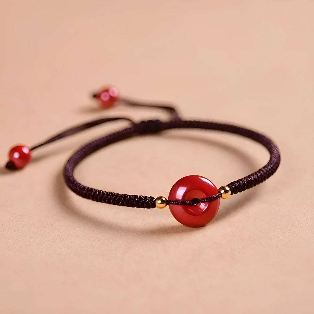 Heart-shaped cinnabar bead on an adjustable knot rope bracelet with a decorative peace buckle closure.