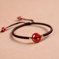 Heart-shaped cinnabar bead on an adjustable knot rope bracelet with a decorative peace buckle closure.