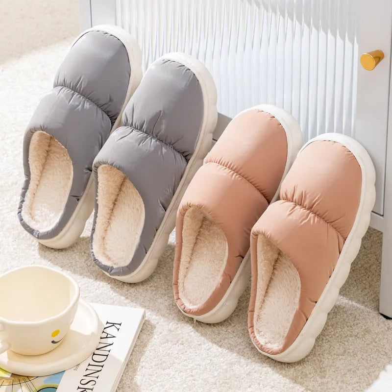 Blue down cotton indoor slippers with thick rubber sole and plush lining on a wooden floor.