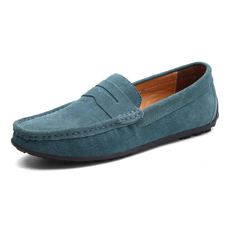 Men's suede slip-on loafers in black on a flat rubber sole, showing round toe and sewing detail.