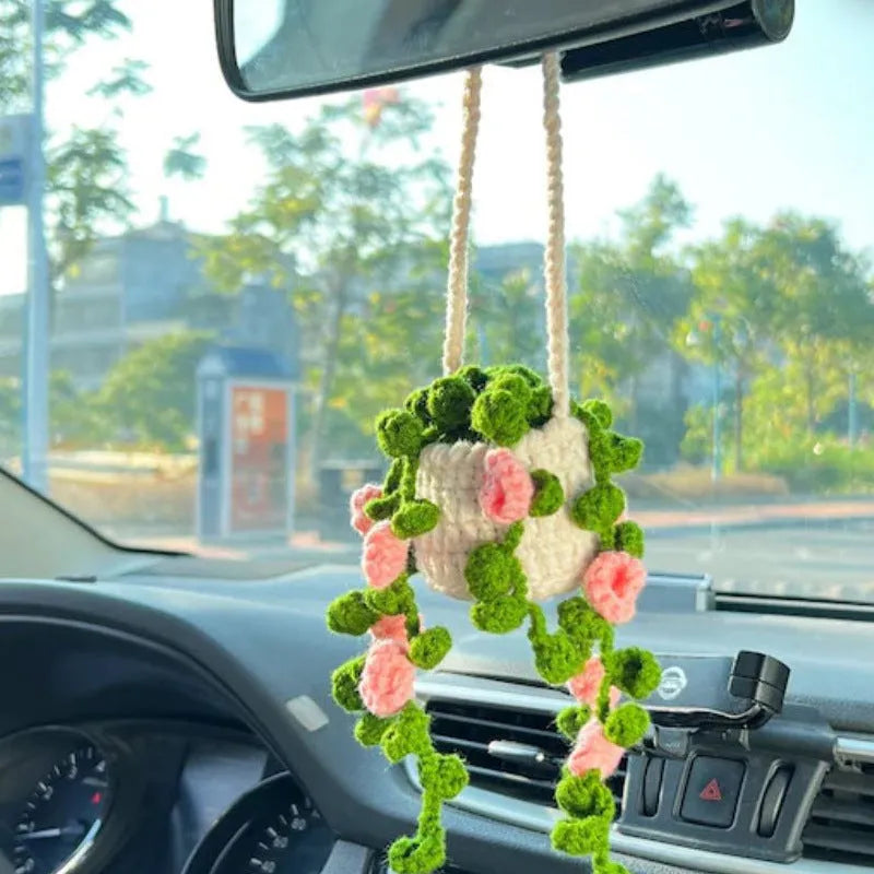 Green and white crochet wool car plant decoration with hanging rope on car dashboard