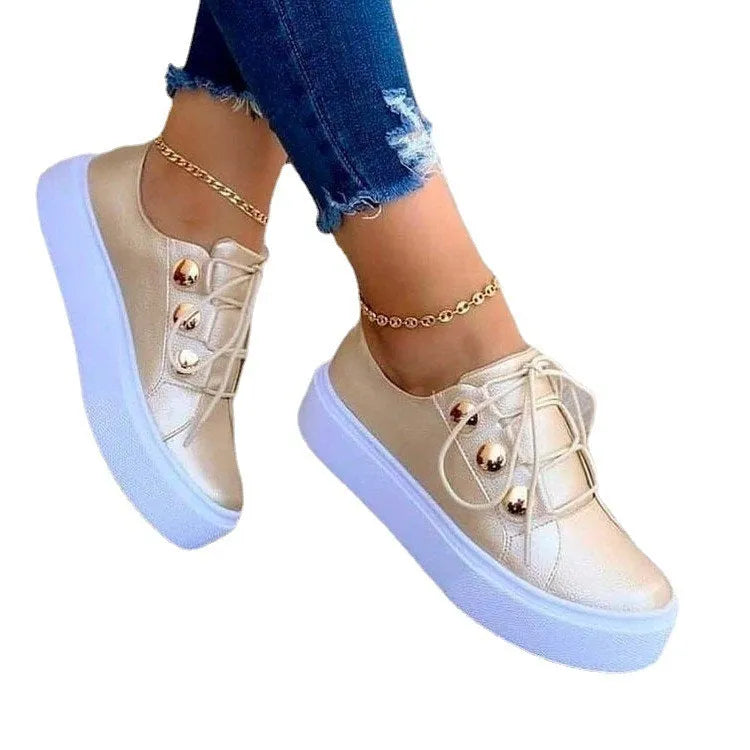 Women's white lace-up flats sneakers with silver rivet details on the low upper and a round toe.