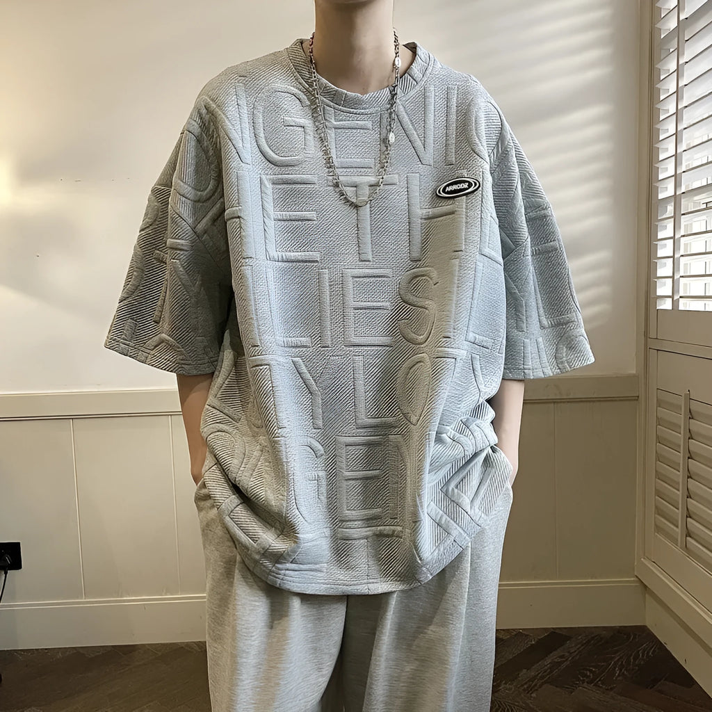 Men's grey loose-fit T-shirt with a raised white three-dimensional letter print on the chest.