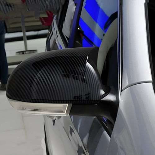 Pair of plastic Volkswagen Sagitar mirror housings in bright black and carbon fibre style finishes.