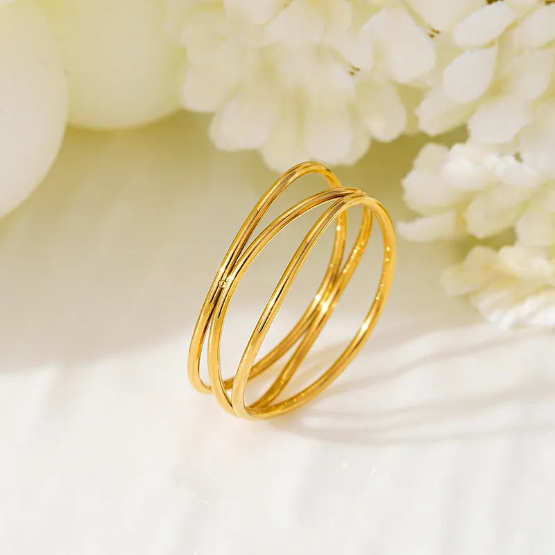 Gold titanium steel ring with a three-layer geometric coil line design on a finger.