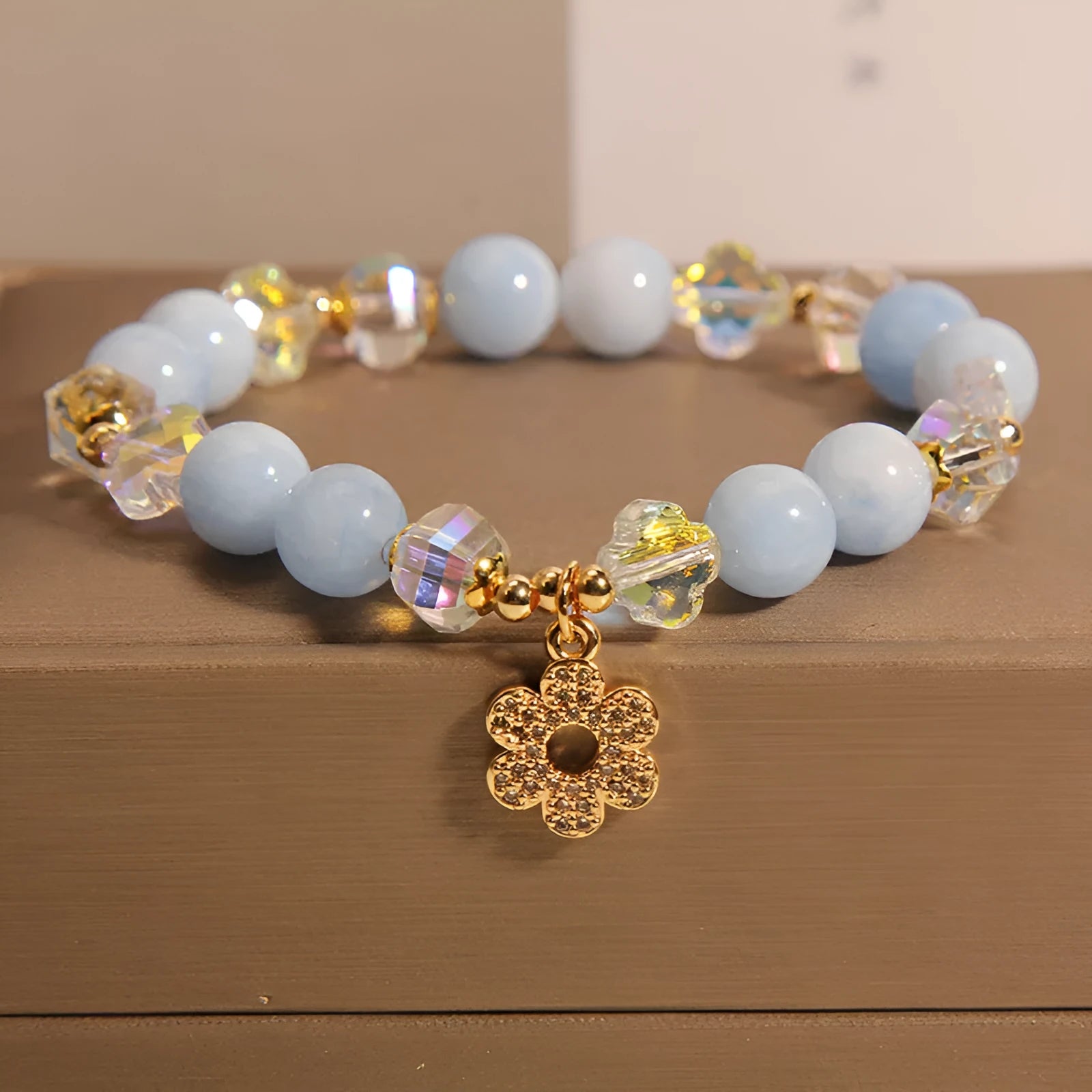 Women's aquamarine crystal bracelet with a four-leaf clover charm and a pearl accent on a model's wrist.