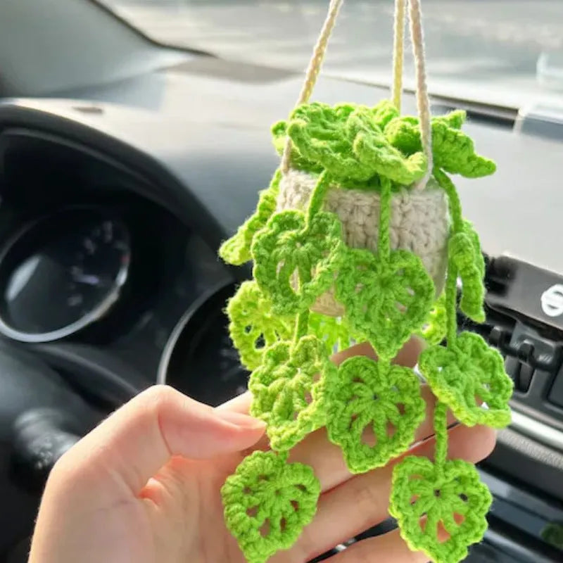 Green and white crochet wool car plant decoration with hanging rope on car dashboard
