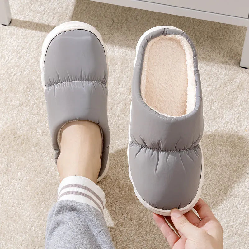 Blue down cotton indoor slippers with thick rubber sole and plush lining on a wooden floor.