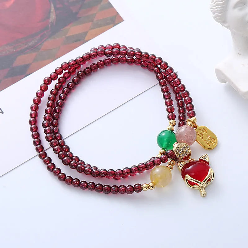 Purplish red rope bracelet with a detailed natural garnet fox pendant and adjustable tie closure.