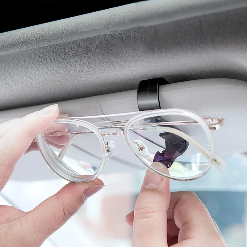 Black plastic car sunshade clip for holding glasses and cards on a vehicle visor.