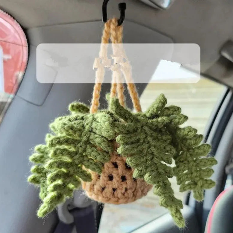 Green and white crochet wool car plant decoration with hanging rope on car dashboard