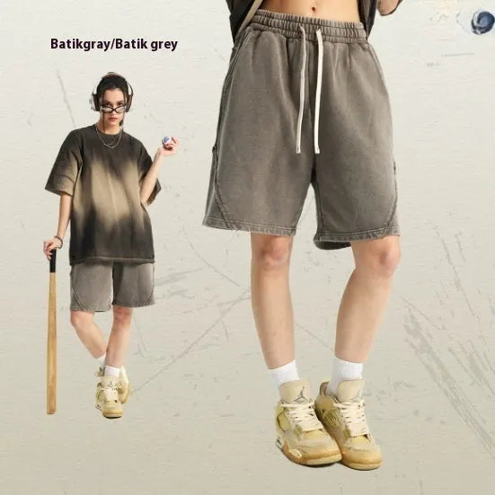 Man wearing loose fit batik washed cotton terry shorts with patch craft detailing in a street fashion style.