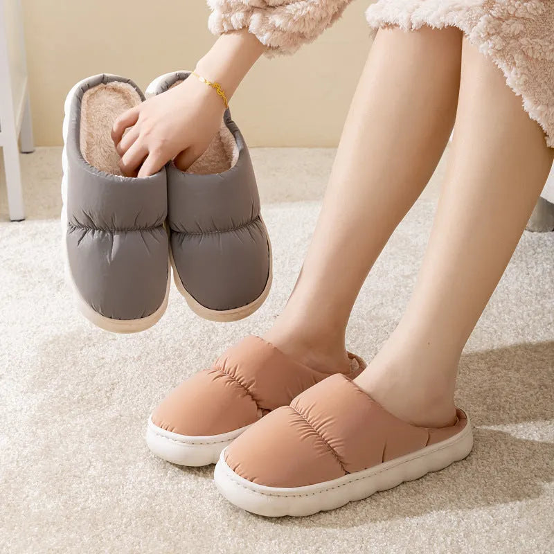 Blue down cotton indoor slippers with thick rubber sole and plush lining on a wooden floor.
