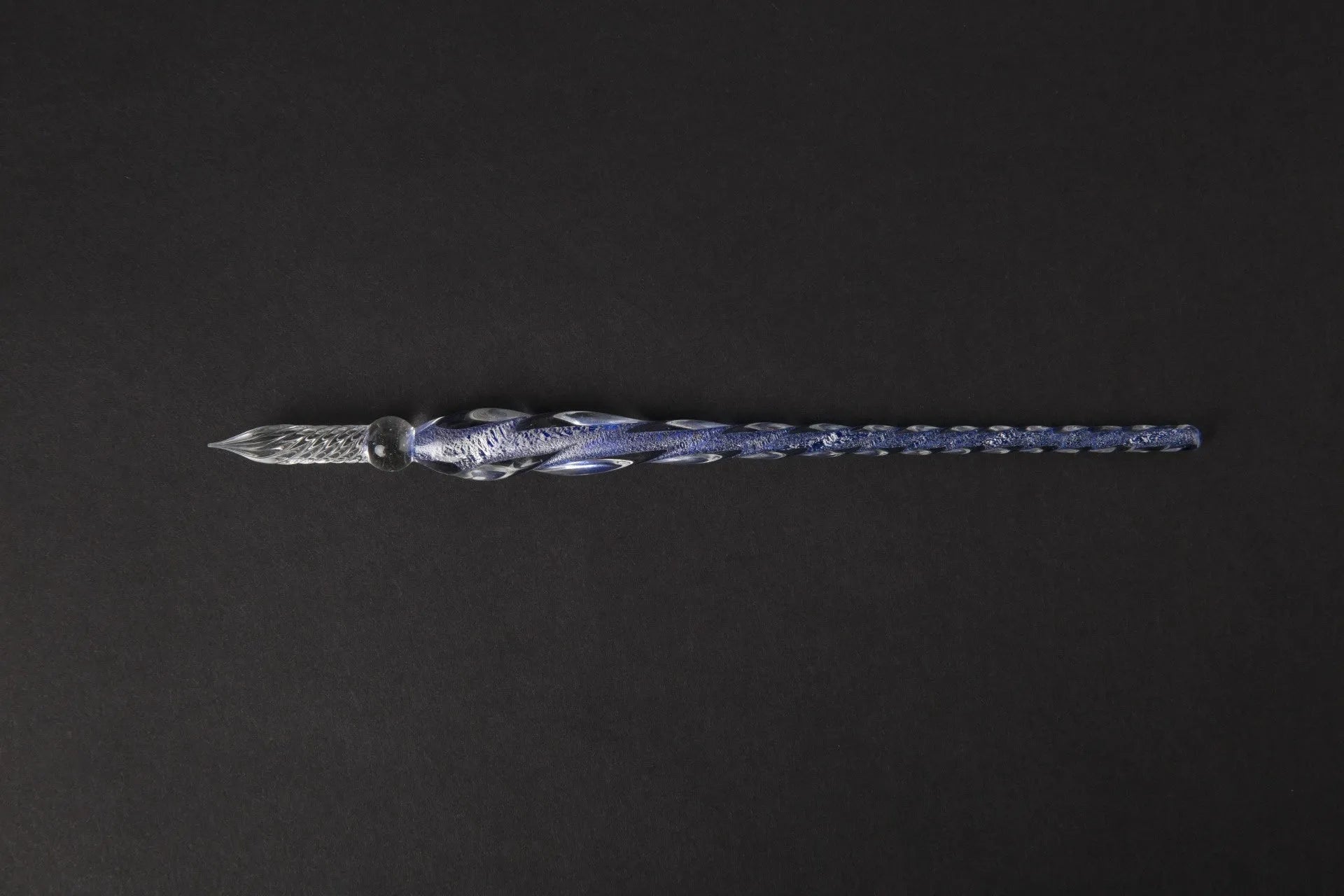Hand-blown glass crystal pen with coloured ink in a transparent barrel on a gift box.