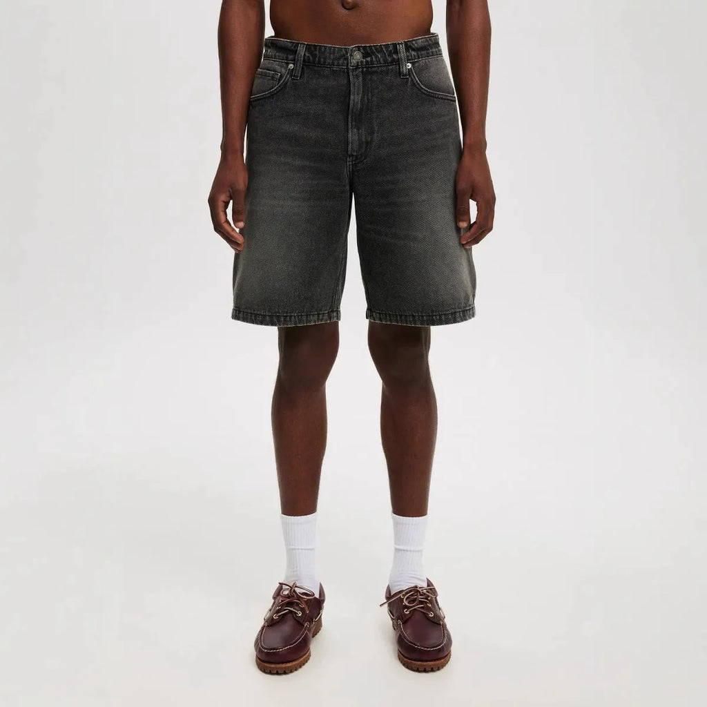 Men's loose straight leg jeans in light blue denim on a plain background