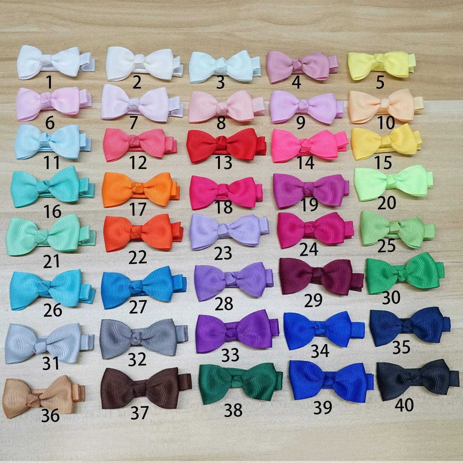 Assortment of pastel-coloured barrette and bow hair clips for babies on a white background.