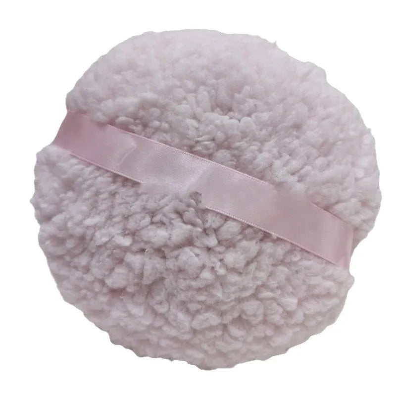 Large oval white plush powder puff for makeup on a plain background.
