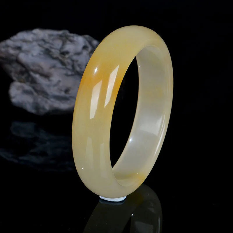 Natural light green jade bracelet in Chinese style, shown on a wrist, with a polished surface.