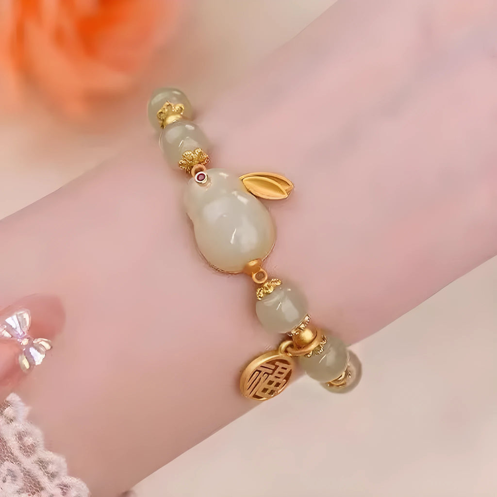 Women's black bracelet with green jade hare charm, fu character, and lily motif detail.