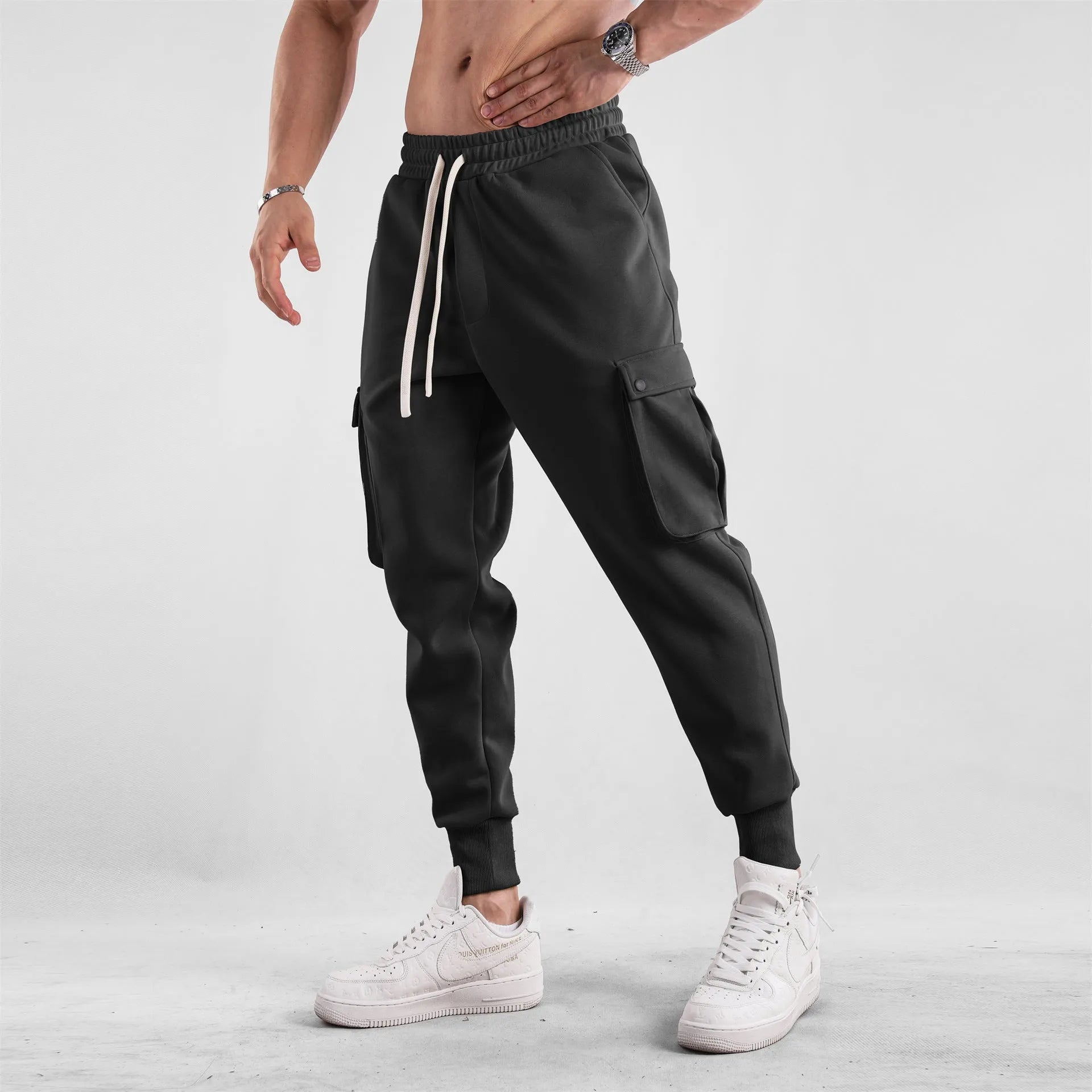 Men's loose fit cotton trousers with ankle-tied cuffs and multiple pockets in a light grey colour.