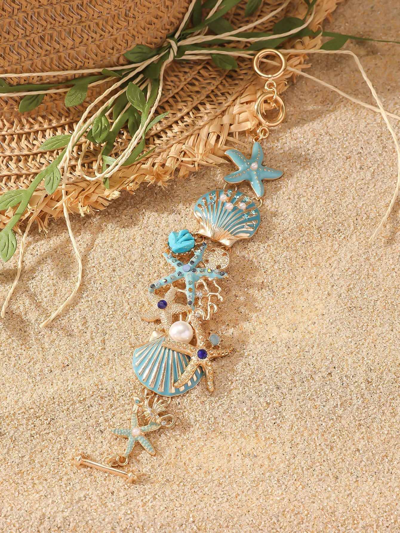 Close-up of a women's alloy bracelet featuring a boat anchor, marine shell, and starfish charms in a coral blue colour.