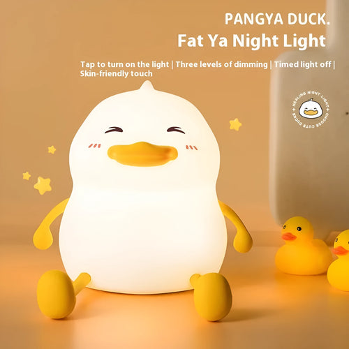 Chubby white rechargeable LED night light with silicone touch top on a wooden desk next to a phone.