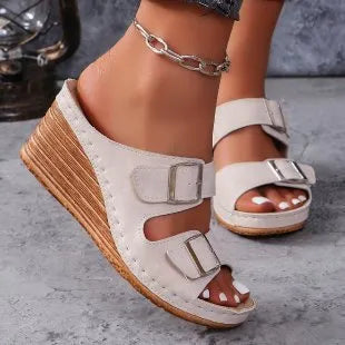 Women's creamy-white beach slippers with a decorative wedge buckle on the strap.
