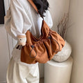 Green ultra-light pleated crossbody student bag showing folding design and split outer pocket