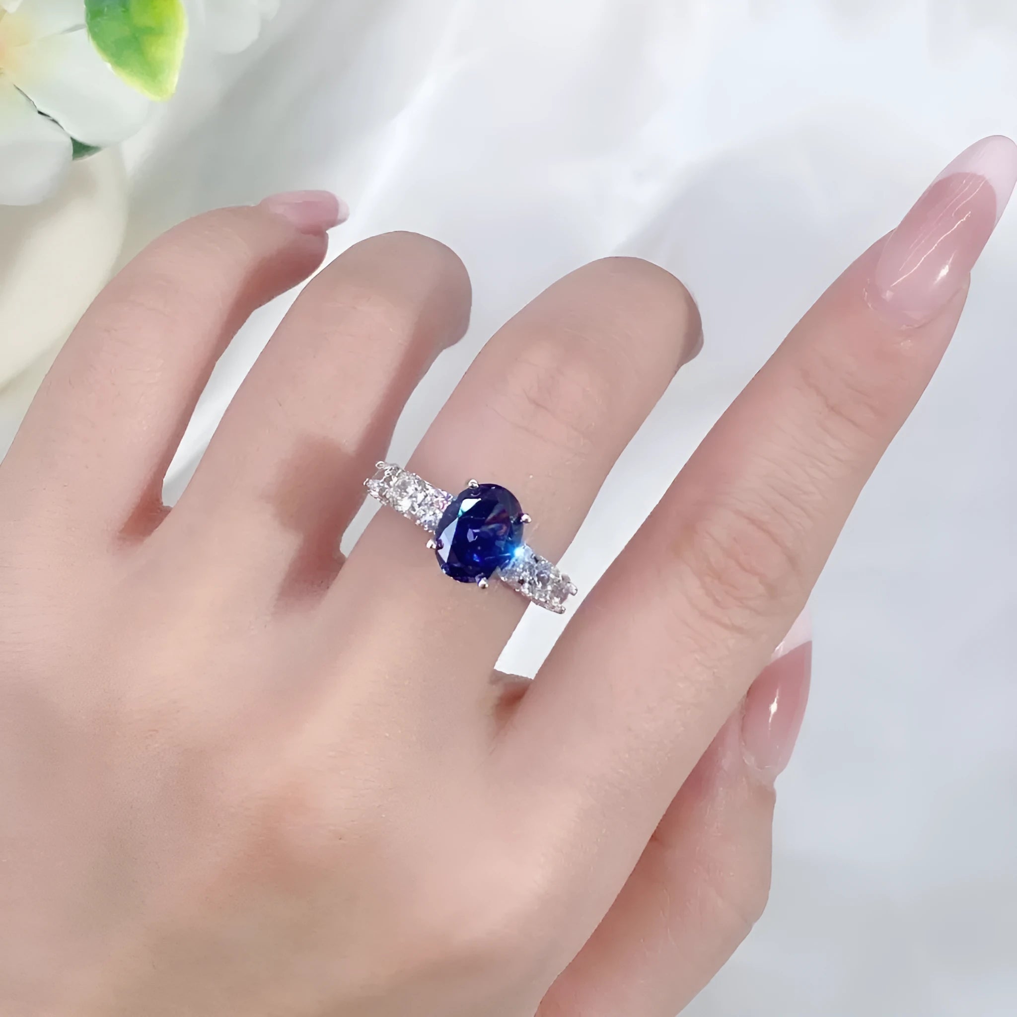 Women's heart-shaped sterling silver ring with ice flower cut coloured zircon stone on finger.
