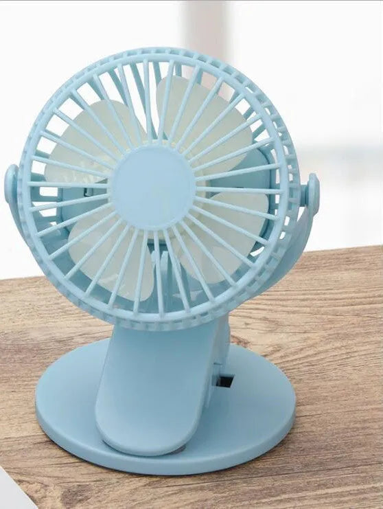 Small white clip fan with USB cable attached to a desk edge