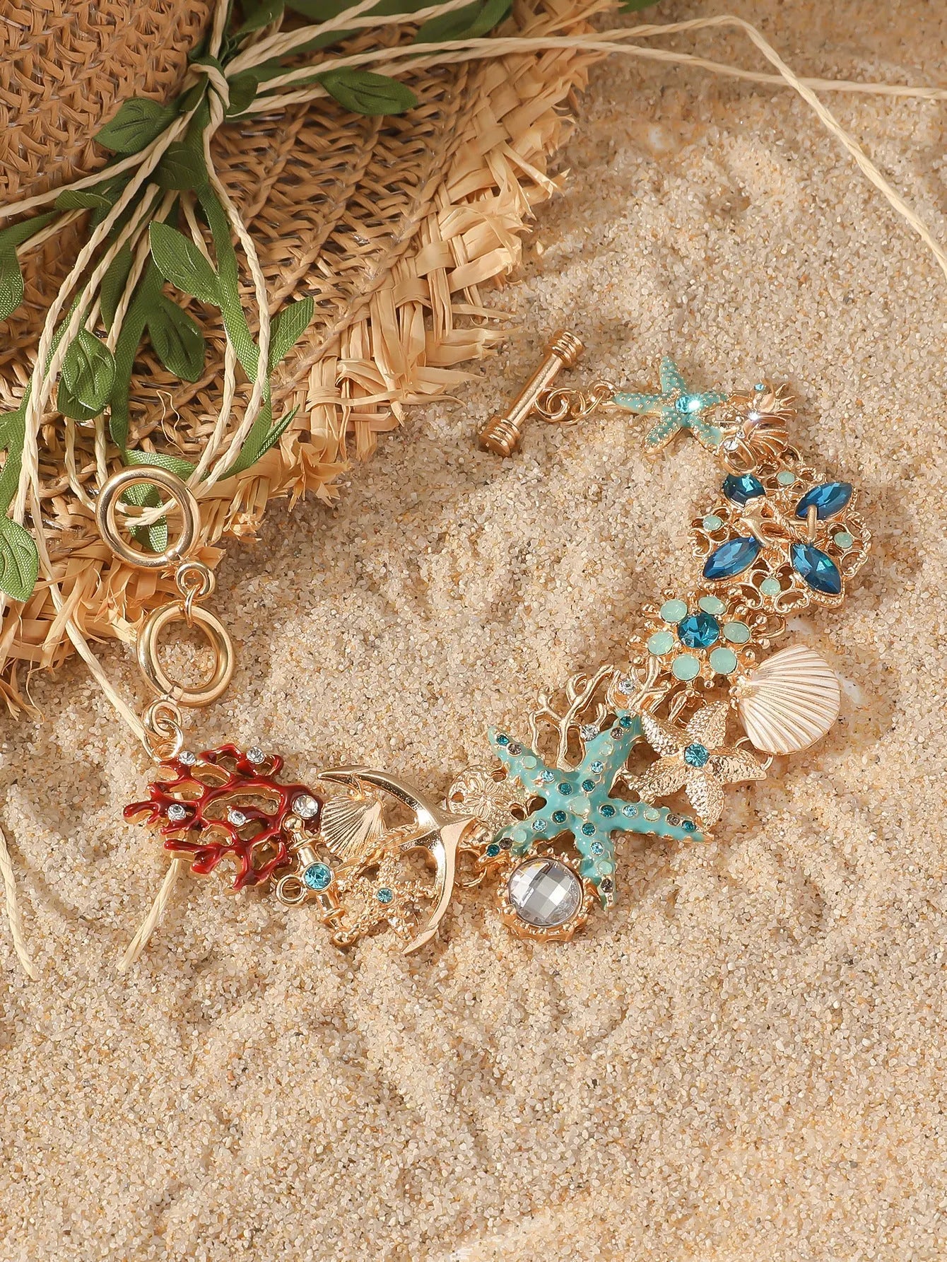 Close-up of a women's alloy bracelet featuring a boat anchor, marine shell, and starfish charms in a coral blue colour.