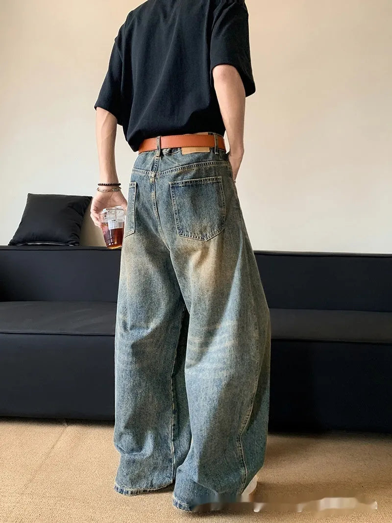 Man wearing retro blue distressed wide-leg denim trousers with a slimming fit.