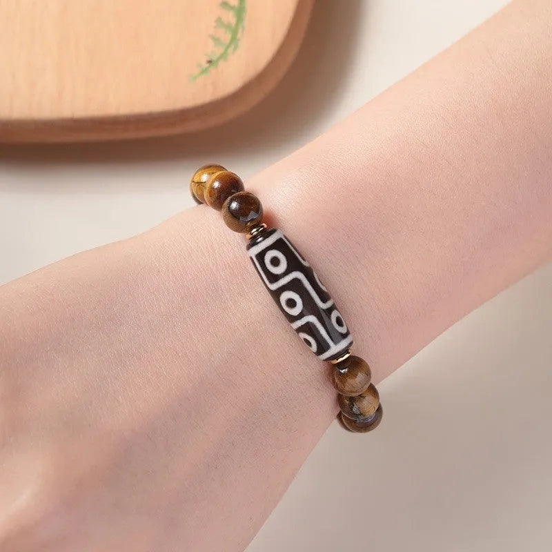 Single circle tigereye stone Buddhist prayer beads bracelet on wrist, showing ethnic design.