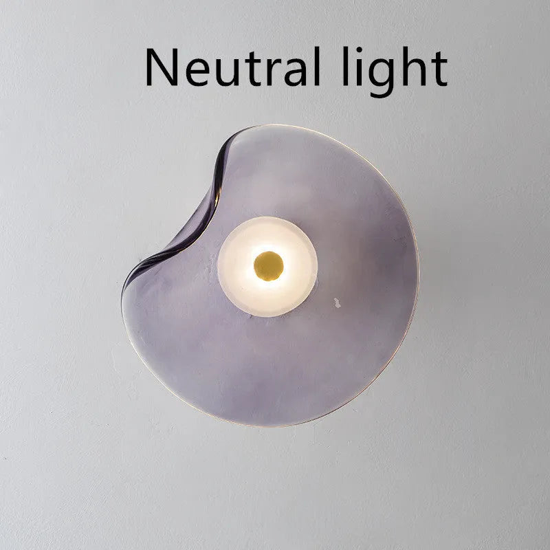Round glass wall lamp in a choice of colours for bedroom bedside lighting.