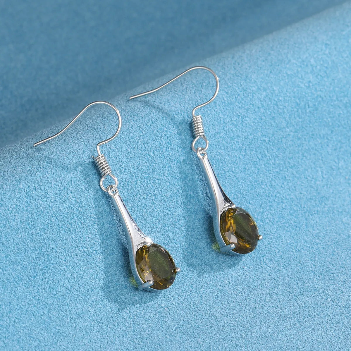 Olive green topaz coloured alloy drop earrings in a water drop shape on a white background.