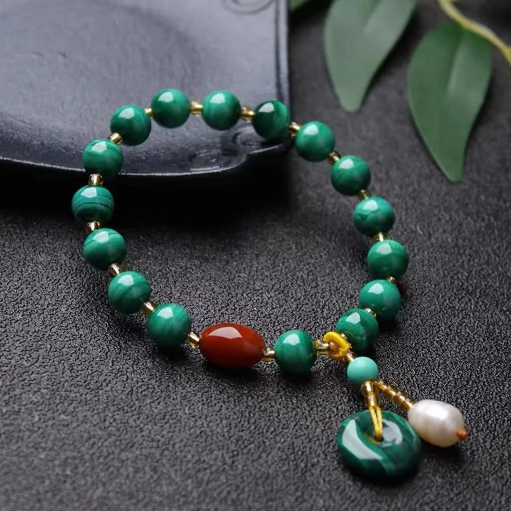 Natural malachite and red agate barrel bead bracelet with silver fittings on a woven elastic cord.